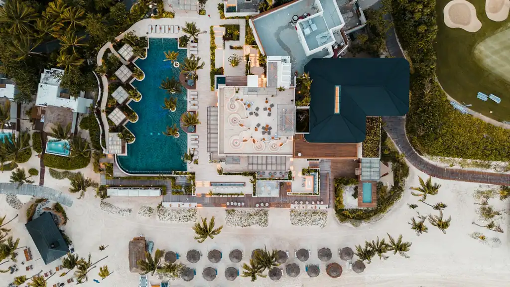 Aerial view of a beachfront resort with pools and palm trees