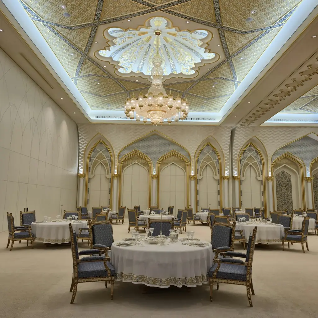 A hotel ballroom set with round tables under a chandelier
