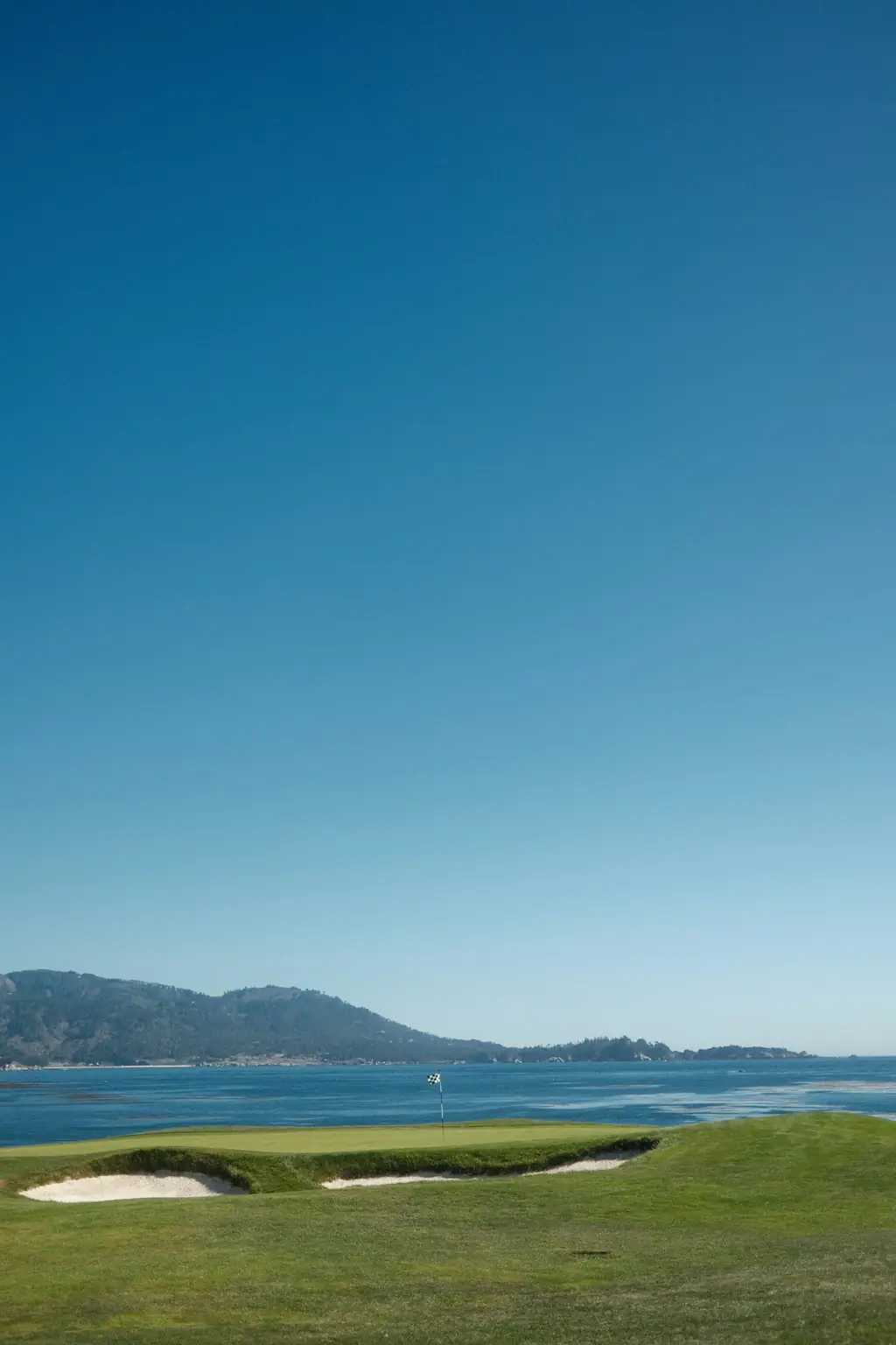 A coastal golf course green beside the ocean