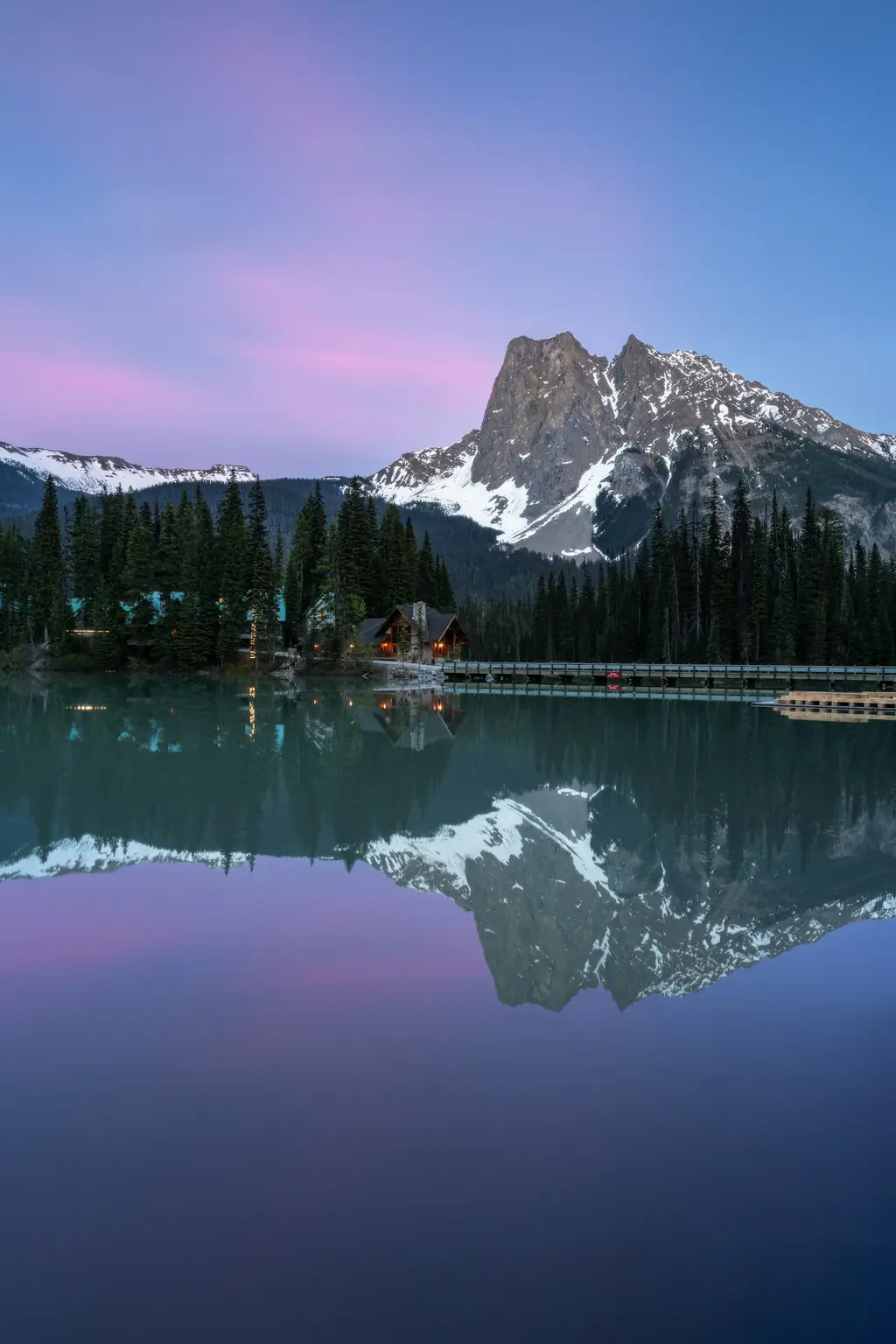 A mountain lake below snow-capped peaks at dusk