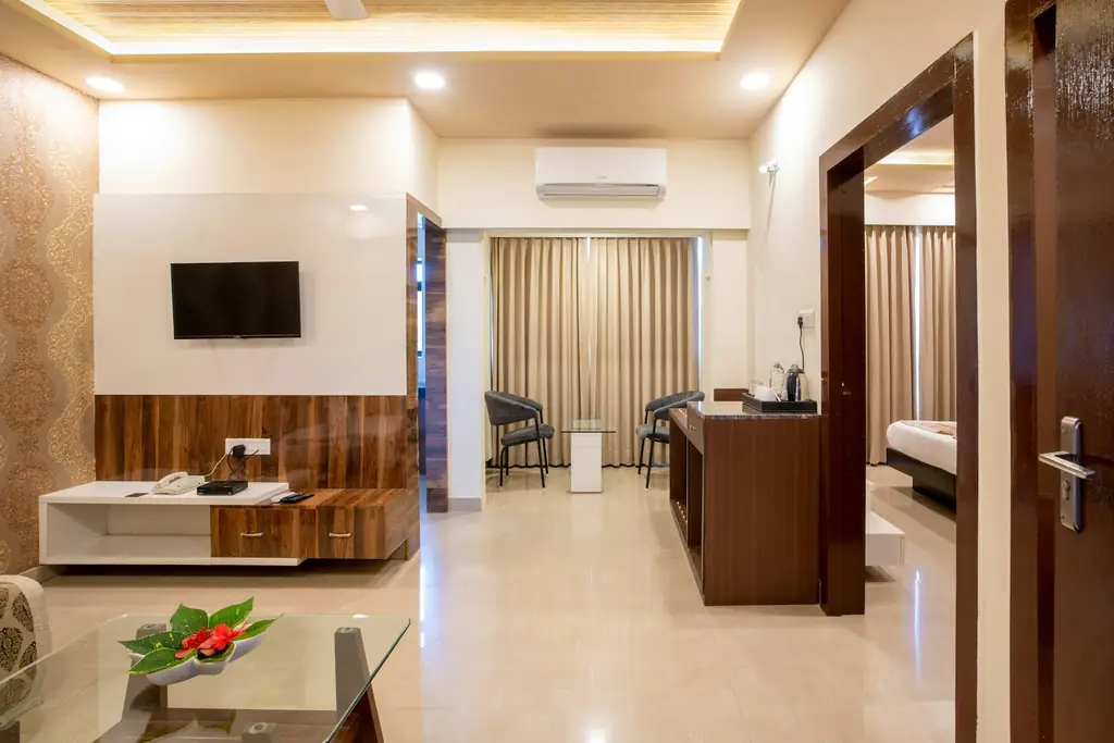 A modern hotel suite with a sofa, a desk and the bedroom beyond